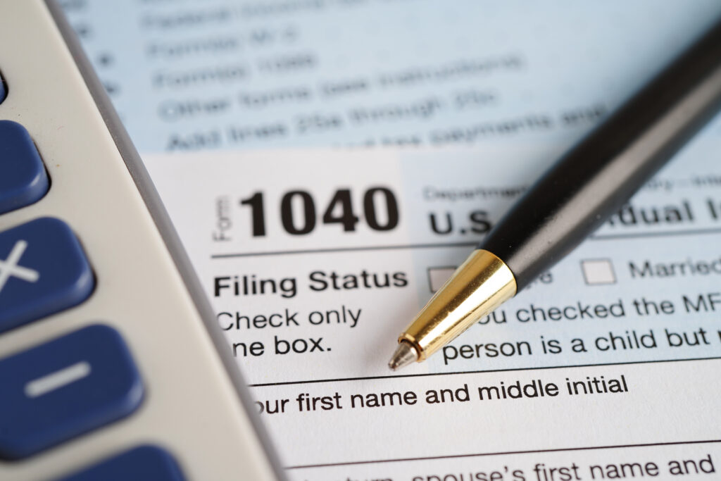 Close-up of a 1040 tax form with a pen resting on the 'Filing Status' line.